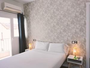 een slaapkamer met een wit bed en een muur bij Hostal Gonzala by gaiarooms in Salamanca