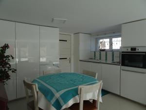 een keuken met een tafel en witte kasten bij Appartement bienvenue à la TOSSEN, TY MAM GOZ in Paimpol