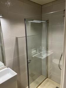 a glass shower in a bathroom with a sink at Panorama Apartment Damsgård in Bergen