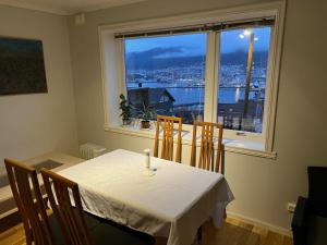 a dining room table with a view of a city from a window at Panorama Apartment Damsgård in Bergen