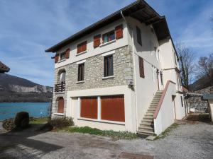 a white building with red garage doors next to a lake at Reflet Bleu du Lac d'Annecy 3 étoiles - Face au lac, Parking gratuit, Paddle board in Doussard