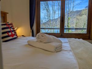 a bed with two towels on it with a window at Reflet Bleu du Lac d'Annecy 3 étoiles - Face au lac, Parking gratuit, Paddle board in Doussard