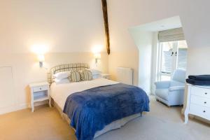a bedroom with a bed and a blue chair at The Old Stables, Derrydown Farm in Andover