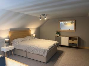a bedroom with a bed and a dresser and a mirror at The Dairy in Castle Douglas