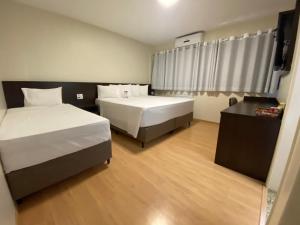 ein Hotelzimmer mit 2 Betten und einem Schreibtisch in der Unterkunft HD Plaza Hotel in Assis
