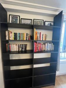 a black book shelf filled with books at Vibrant & Homely 2BD Flat - Angel in London