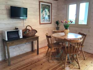 a dining room with a table and a television at Tranquil Log Cabin - Beautiful Rural Sunset Views in Weston Longville