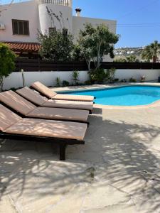 a group of lounge chairs next to a swimming pool at Villa Kokkinoyia, in Peyia