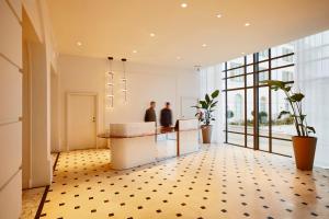 a lobby with a counter and a person in the background at La Licorne Hotel & Spa Troyes - MGallery Collection in Troyes +97 photos