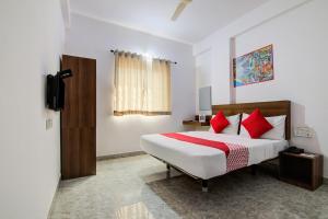 1 dormitorio con 1 cama grande con almohadas rojas en Varcity Comforts Near Ragigudda Sri Prasanna Anjaneyaswamy Temple en Bangalore