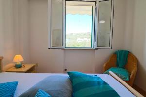 ein Schlafzimmer mit einem Bett, einem Fenster und einem Stuhl in der Unterkunft Casa vacanze La Perla a Castro in Castro di Lecce