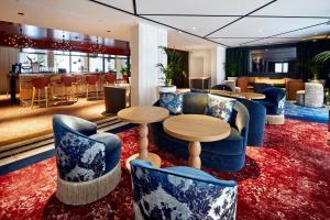 a lobby with blue chairs and tables on a red rug at La Licorne Hotel & Spa Troyes - MGallery Collection in Troyes