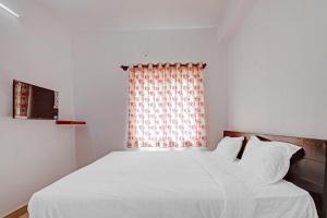- un lit blanc dans une chambre avec fenêtre dans l'établissement OYO Green Residency, à Bangalore