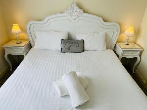 Una cama blanca con 2 mesitas de noche con toallas. en Heath Cottage Hotel, en Dewsbury