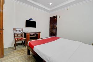 a bedroom with a bed and a desk and a television at OYO Royal Grand Residency Near Lalbagh Botanical Garden in Bangalore
