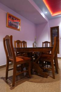 a wooden dining room table with wooden chairs and a table at Ammukutty's Cottage in Munnar
