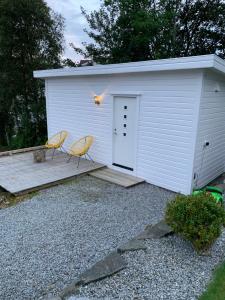 uma pequena garagem branca com duas cadeiras em frente em Sjøberg Ferie og Hotell em Østhusvik