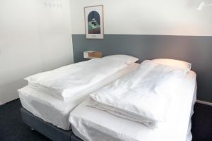 Eiðar - Hostel في Eiðar: سريرين في غرفة ذات أغطية بيضاء
