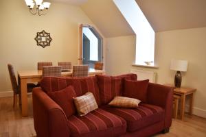 a living room with a red couch and a table at The Ross 2 bedroom apartment in historic Abbey in Fort Augustus