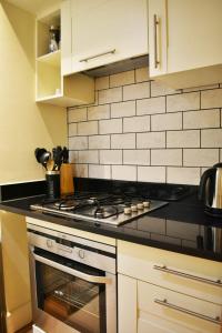 a kitchen with a stove top oven and white cabinets at The Ross 2 bedroom apartment in historic Abbey in Fort Augustus