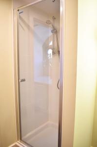 a shower with a glass door in a bathroom at The Ross 2 bedroom apartment in historic Abbey in Fort Augustus