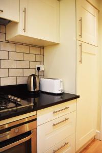 a kitchen with white cabinets and a toaster on a counter at The Ross 2 bedroom apartment in historic Abbey in Fort Augustus