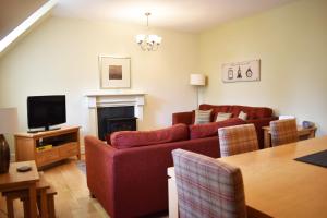 a living room with a red couch and a fireplace at The Ross 2 bedroom apartment in historic Abbey in Fort Augustus