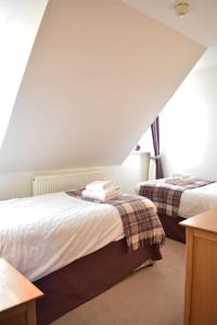 two beds in a room with an attic at The Ross 2 bedroom apartment in historic Abbey in Fort Augustus