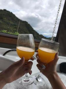 two people holding up two glasses of beer at Chalé Araucária- Vale das Pedras MG in Sapucaí-Mirim