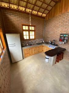 a kitchen with a refrigerator and a table in it at Chalé Araucária- Vale das Pedras MG in Sapucaí-Mirim
