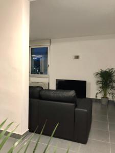 a black leather couch in a living room with a window at Appartement de 110m2 au centre de Cusset in Cusset