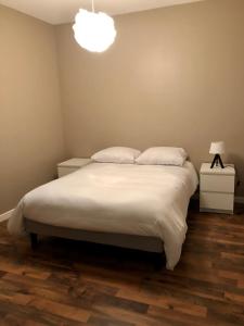 1 dormitorio con 1 cama con sábanas blancas y lámpara en Appartement de 110m2 au centre de Cusset, en Cusset
