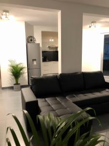 sala de estar con sofá negro y cocina en Appartement de 110m2 au centre de Cusset, en Cusset
