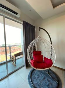 una silla colgante con almohadas rojas en una habitación con ventana en One Residence Sekinchan 适耕庄无敌海景, en Sekinchan