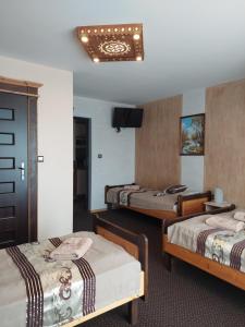 a hotel room with three beds and a television at Noclegi Emma - Pokoje Gościnne in Gliczarów