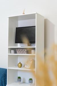 un centro de entretenimiento blanco con TV de pantalla plana en Athenais Apartment, en Lixouri