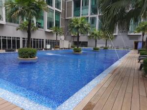 a large blue swimming pool with palm trees in front of a building at 3ROOMS SOHO SUITES KLCC BY RED HOMES in Kuala Lumpur