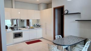 a kitchen with white cabinets and a table with chairs at 3ROOMS SOHO SUITES KLCC BY RED HOMES in Kuala Lumpur