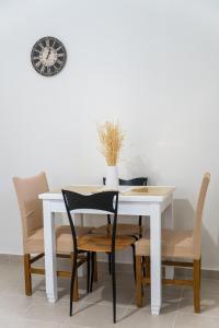 mesa de comedor blanca con sillas y reloj en Athenais Apartment, en Lixouri