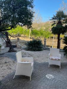 2 sedie bianche sedute su un patio in mattoni di La casa di Cinzia, Pompei/Vesuvio a Palma Campania