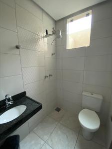 een witte badkamer met een toilet en een wastafel bij Pousada Elita in Divinópolis
