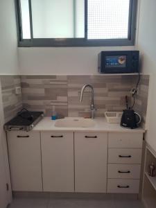 a kitchen with white cabinets and a sink and a window at Puy Rambam's apartment Tiberias in Tiberias