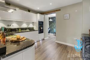 una cucina con armadi bianchi e piano di lavoro di La Petite Maison Apartments a Brixham