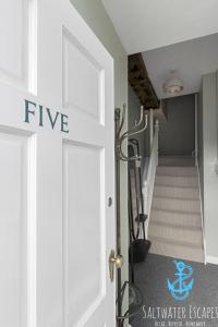 un pasillo con una puerta blanca con escalera en La Petite Maison Apartments en Brixham