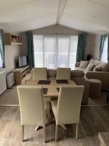uma sala de estar com uma mesa e cadeiras e um sofá em Kellysholidayhomes NEW Malton 3 bedroom Caravan em Weeley