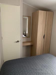 a bedroom with a bed and a wooden cabinet at Kellysholidayhomes NEW Malton 3 bedroom Caravan in Weeley