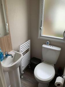 a bathroom with a white toilet and a sink at Kellysholidayhomes NEW Malton 3 bedroom Caravan in Weeley