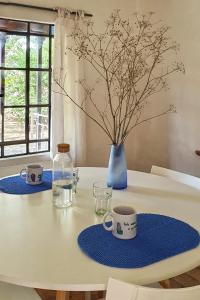 Una mesa con dos tazas y un jarrón azul. en Casa La Raquelita en Navarro