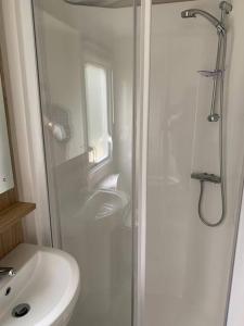 a white bathroom with a sink and a shower at Kellysholidayhomes NEW Malton 3 bedroom Caravan in Weeley