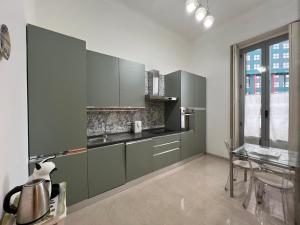 cocina con armarios verdes y mesa de cristal en IMHOME - Cadorna House, en Milán